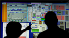 Two scientists looking at a large monitor in the accelerator control room at Jefferson Lab