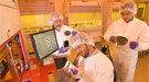 Three scientists in front of a computer station.