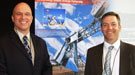 Two men in suits standing in front of an exhibit display