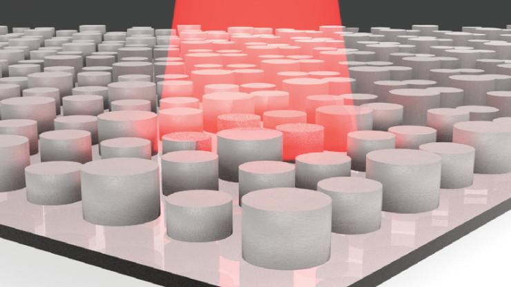 Many white cylinders on a shiny white surface with a beam of red coming from the top.